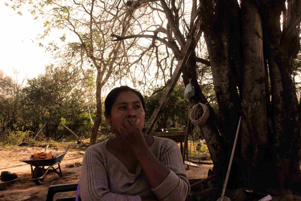 Gabriela Araguino, productora de miel de Tahiguaty, bajo un árbol en su comunidad, reflexionando sobre su trabajo apícola.