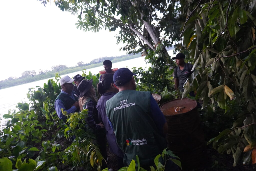 Autoridades del Tribunal Agroambiental y fuerzas del orden inspeccionan turriles y otros desechos de la actividad minera ocultos entre la vegetación ribereña en territorio del pueblo indígena Esse Ejja, durante la visita realizada el 4 de febrero en el río Madre de Dios.